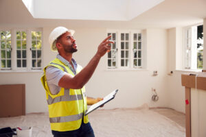 Building Inspector Wearing Hard Hat With Clipboard Looking At Interior Of New Property